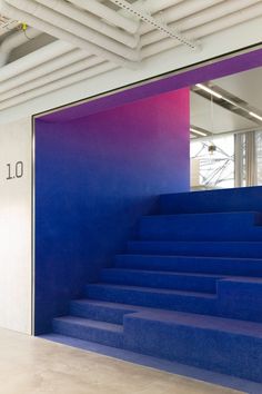 blue stairs leading up to the top floor in an office with pink and purple walls