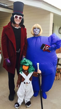 two people in costumes standing next to each other on a porch with an inflatable character behind them