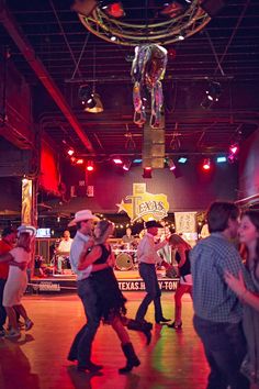 a group of people dancing on a dance floor in a room with disco lights and decorations