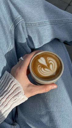 a person is holding a cup of coffee in their left hand while sitting on the ground