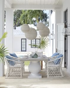 a white table with blue chairs and hanging lanterns