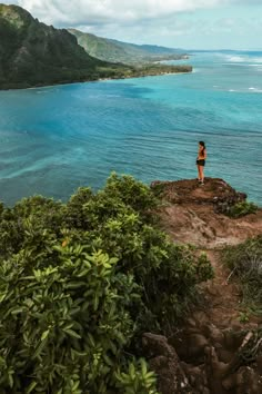 a woman standing on top of a cliff overlooking the ocean