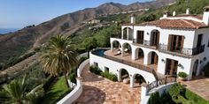 an aerial view of a large house with mountains in the back ground and palm trees on either side