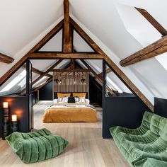 an attic bedroom with two green chairs and a bed