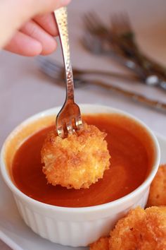 a person is holding a fork with some food in it and dipping sauce on the other side