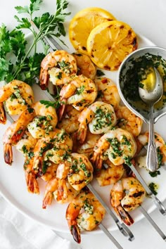 grilled shrimp with parsley and lemon on a white plate next to silver serving utensils