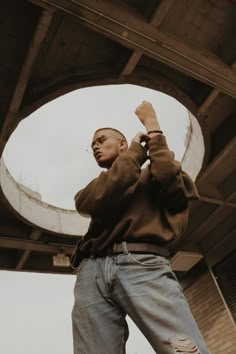 a man standing in front of an overpass with his hands up to the ceiling