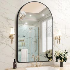 a bathroom sink sitting under a mirror next to a vase with flowers on top of it