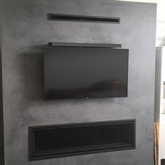 a flat screen tv mounted to the side of a wall next to a fire place