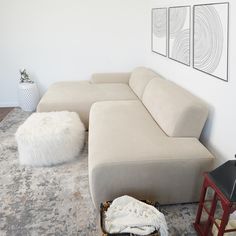 a living room with a large sectional couch and white rugs on the floor in front of it