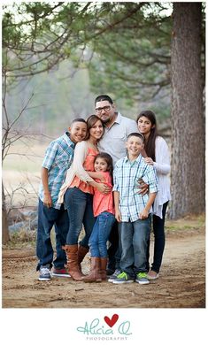 a family posing for a photo in front of some trees and dirt road with the caption above it