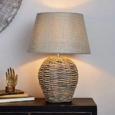 a table with a lamp on top of it next to a book and a basket