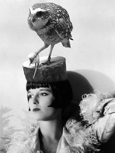 a woman with an owl on top of her head and another bird perched on the back of her head