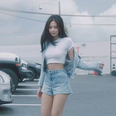 a woman standing in the middle of a parking lot with her arms out and one hand on her hip