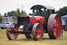 an old fashioned tractor is parked in the grass