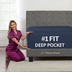 a woman in purple is pointing to the bed with it's mattress and headboard