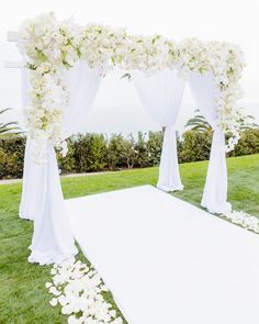 an outdoor wedding setup with white flowers and draping