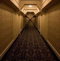 an empty hallway leading to another room in a hotel or other building with carpeted flooring