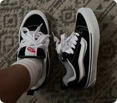 someone wearing black and white vans with red logo on them