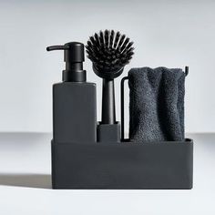 a black soap dispenser, brush and towel on a white table top