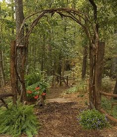 a wooden arch in the middle of a forest filled with trees and flowers, surrounded by greenery