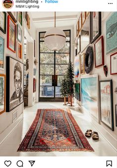 the hallway is decorated with many framed pictures and rugs on the floor, along with a potted plant