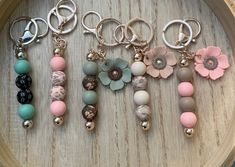 six different key chains with flowers on them sitting on a wooden tray next to each other