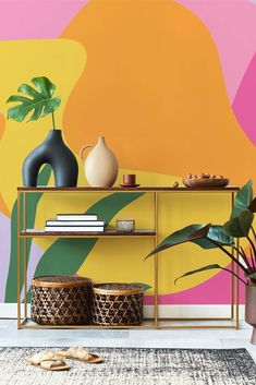 a shelf with vases and plants on it in front of a colorful wall