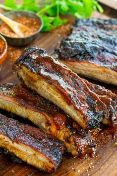 barbecue ribs on a cutting board with dipping sauces