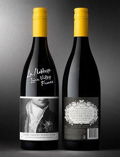 two bottles of wine sitting next to each other on a gray surface with yellow caps