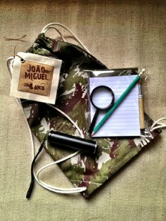 an assortment of items including a notepad, pen and magnifying glass on a fabric bag