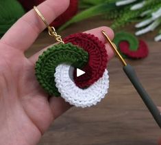 someone is holding a crocheted keychain with an apple in the center