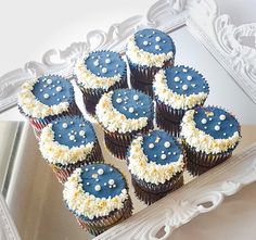 cupcakes with blue frosting and white sprinkles in front of a mirror