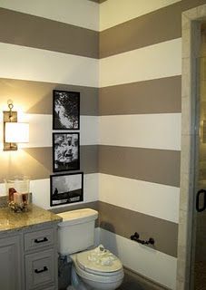 a bathroom with gray and white stripes painted on the walls, toilet and vanity area