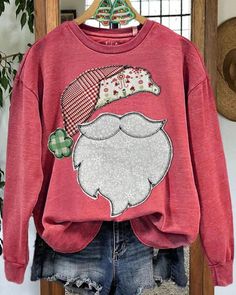 a red sweatshirt with a santa clause graphic on the front and back, hanging from a wooden hanger