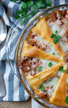 a casserole dish filled with meat, cheese and parsley on top of a table