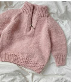 a pink sweater on top of a bed