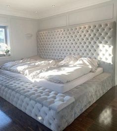 a large bed sitting in the middle of a room next to a window with sunlight streaming through it