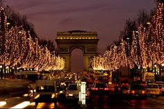 the arc de trioes is lit up with christmas lights and trees on both sides