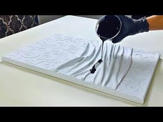 a person pouring something into a cup on top of a mattress that has been made