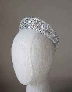 a white headpiece on top of a mannequin's head wearing a tiara