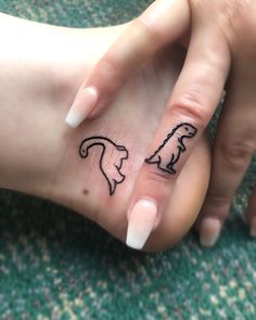 two hands holding each other with small tattoos on their thumbnails and one has a dog's head drawn on it