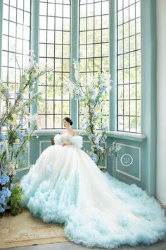 a woman in a blue gown sitting on a bench