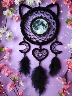 a black cat dream catcher with feathers hanging from it's side and a full moon in the background