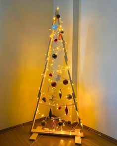 a lighted christmas tree in the corner of a room with wooden flooring and white walls