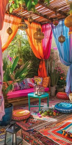 an outdoor living area with colorful curtains and rugs on the floor, potted plants