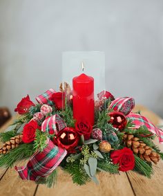 a christmas centerpiece with red candles and greenery