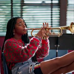 a woman sitting in a chair playing a trumpet