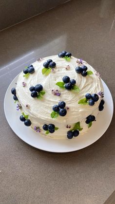 a white cake with blueberries and green leaves on it