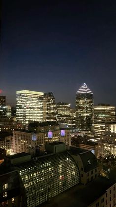 the city skyline is lit up at night with skyscrapers in the foreground and lights on